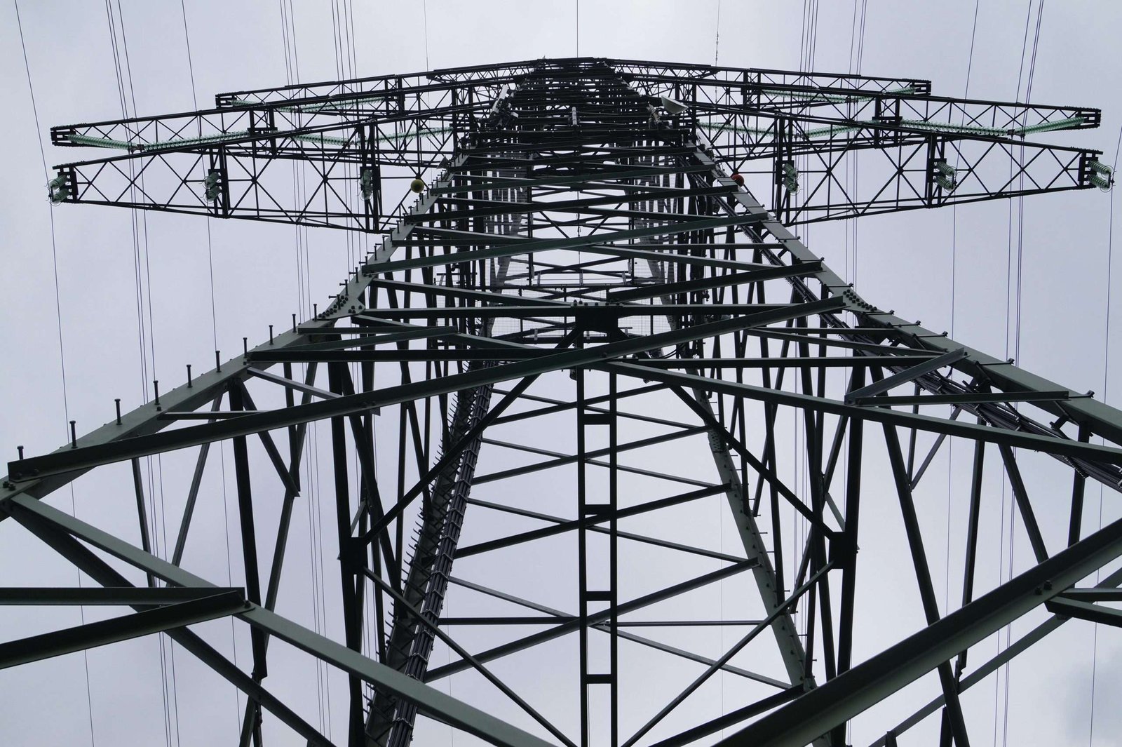 Close-up low angle view of a metal electricity pylon against a cloudy sky.